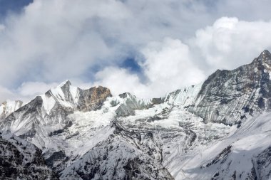Nepal, Annapurna Sığınağı 'ndaki karla kaplı dağların manzarası. Tepeler bulutlu bir gökyüzüne yükselir. Annapurna Kampı yakınlarındaki Himalayalar 'da..