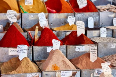 Harissa ve Paprika gibi çeşitli renkli baharatlar, Marakeş 'teki bir baharat pazarında fiyat etiketleriyle metal kaplarda sergileniyor.