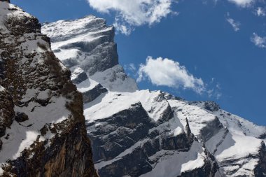 Himalayalar, Nepal 'deki karlı dağların görkemli manzarası Annapurna Ana Kampı' na giden popüler güzergahta dağınık mavi bulutlarla dolu bir gökyüzünün altında ilerliyor..