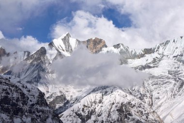 Annapurna Ana Kampı yakınlarındaki Himalayalar 'da karla kaplı bir kule. Bulutlar Annapurna Sığınağı, Nepal 'deki tepelerde sürükleniyor.