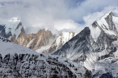 Annapurna Sığınağı 'nda karla kaplı bir kule. Bulutlar Himalayalar ve Nepal 'deki dağ zirvelerini kısmen karalıyor.
