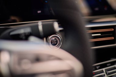 Direksiyonun arkasındaki torpido gözünün açma ve durdurma düğmesine bakıyorum. Arabanın içi modern ve temiz görünüyor. Otomobil düğmesine bas.