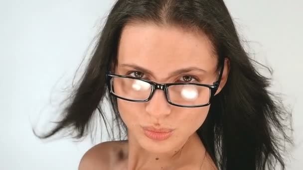 Retrato de uma menina com cabelos longos, ela posa em óculos em um fundo branco, câmera lenta, 100fps — Vídeo de Stock