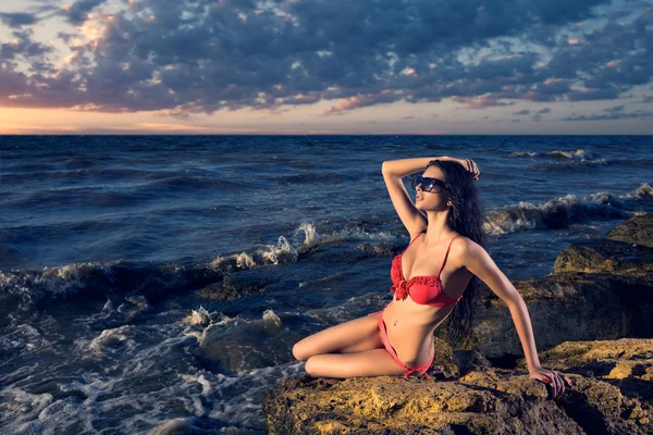Young girl in a swimsuit on the rocks near the sea — Stock Photo, Image