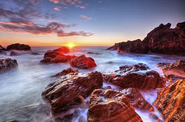 Salida del sol en la costa rocosa y nubes de cielo dramáticas — Foto de Stock