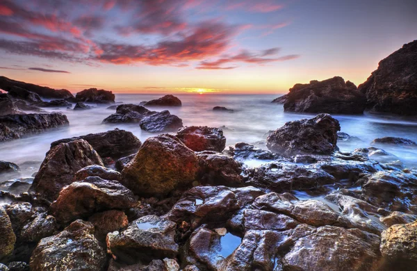 Salida del sol en la costa rocosa y nubes de cielo dramáticas — Foto de Stock