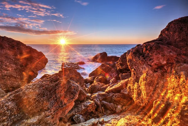 Salida del sol en la costa rocosa y nubes de cielo dramáticas — Foto de Stock