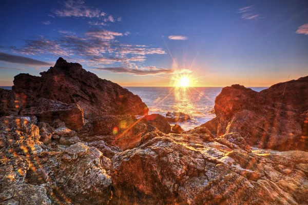 Salida del sol en la costa rocosa y nubes de cielo dramáticas — Foto de Stock