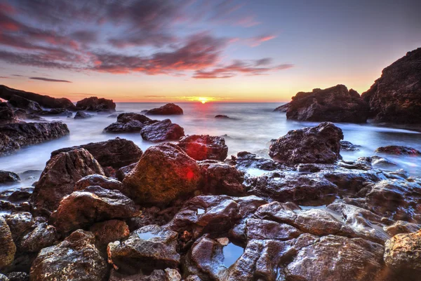 Salida del sol en la costa rocosa y nubes de cielo dramáticas — Foto de Stock