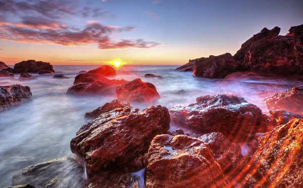 Salida del sol en la costa rocosa y nubes de cielo dramáticas — Foto de Stock