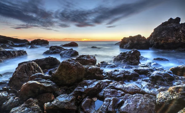 Salida del sol en la costa rocosa y nubes de cielo dramáticas — Foto de Stock