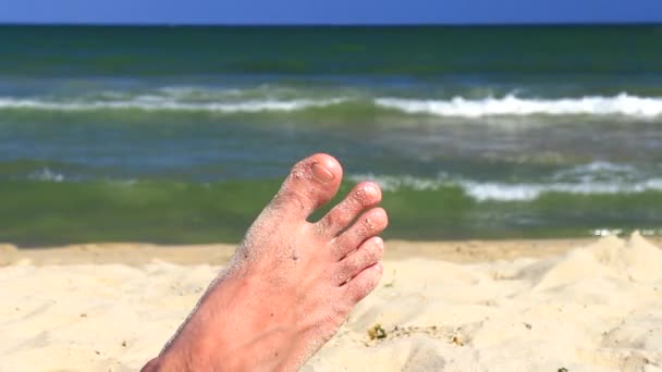 Männlicher Fuß am Sandstrand und in den Wellen des Meeres — Stockvideo