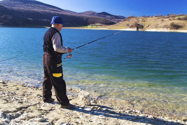 Pescatore pesca sul lago blu — Foto Stock