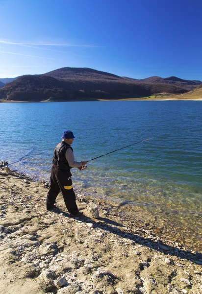 Pescador pescando en el lago azul — Foto de Stock