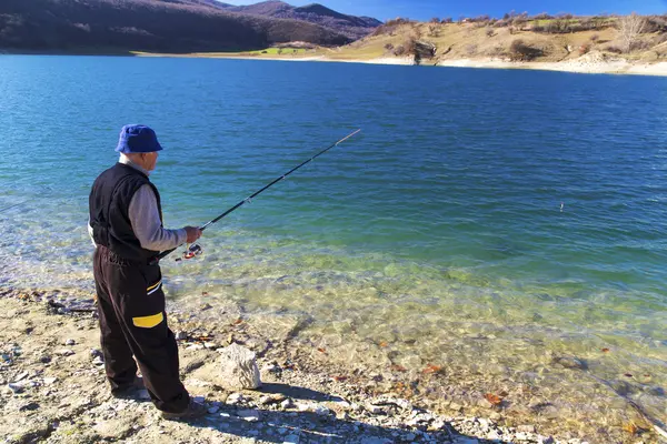 Pescatore pesca sul lago blu — Foto Stock