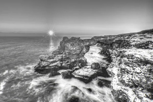 Belo nascer do sol sobre o mar e costa rochosa em preto e branco — Fotografia de Stock