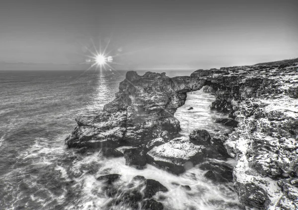 Beautiful sunrise over the sea and rocky shore on black and white — Stock Photo, Image