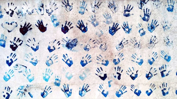 on the concrete wall are the prints of many human hands that were dipped in paint
