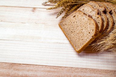 Lezzetli ekmek. Buğday tohumu kulaklı bir somun taze ekmek ya da ahşap desenli bir bitki. Çavdar ekmeği ve ekmek kırıntılarıyla. Ev yapımı pişirme.