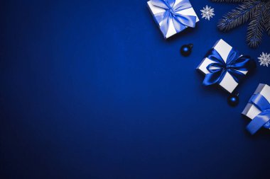 Kış tasarımı Cyan kurdeleli beyaz hediye kutusu, yılbaşı baloları ve tebrik kartı için koyu mavi arka planda kış ağacı. Metin için alanı olan Xmas arkaplanı