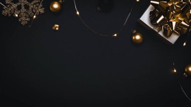 Sürpriz kutu. Altın yay, altın toplar ve parlak ışık çelenkleriyle dolu beyaz bir hediye. Karanlık arka planda tebrik kartı için. Düz konum, üst görünüm, kopyalama alanı