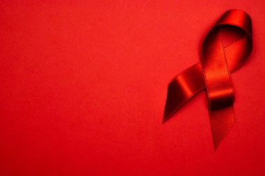 HIV virüsü. HIV dünyasında kırmızı arkaplanda kırmızı kurdele sembolü. Farkındalık yardımcıları ve kanser. Sağlık, tıbbi işaret. Boşluğu kopyala.