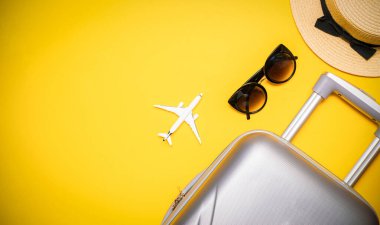 Deniz arka planı. Çantalı seyahat aksesuarları, beyaz bir uçak, sarı arka planda minimum tatil konsepti olan palmiye yaprakları. Yaz tatili ve ürün reklamları konsepti.