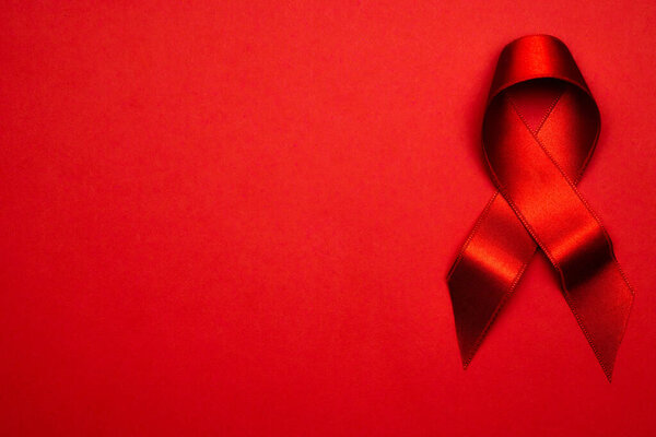 Символ инфекции. Символ красной ленты в День мира ульев на темно-красном фоне. Осведомленность и рак. Здравоохранение и медицина.