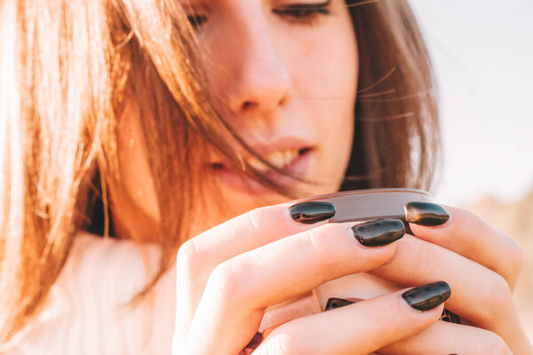 Пьющая чай женщина. Счастливая молодая девушка с чашкой кофе на солнце сидя на открытом воздухе. Чашка горячего напитка.