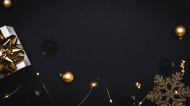 Sürpriz kutu. Altın yay, altın toplar ve parlak ışık çelenkleriyle dolu beyaz bir hediye. Karanlık arka planda tebrik kartı için. Düz konum, üst görünüm, kopyalama alanı