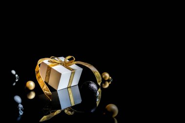 Kış altın madeni. Altın yaylı beyaz hediye, altın toplar ve yeni yıl ağacı. Koyu arkaplanda tebrik kartı için. Metin için alanı olan Xmas arkaplanı