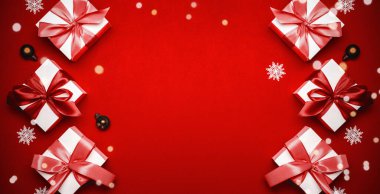 Hediye kurdele kutusu. Kırmızı kurdeleli beyaz hediye kutusu, yılbaşı baloları ve tebrik kartı için koyu kırmızı arka planda parlak ışıklar. Noel, kış, yeni yıl konsepti