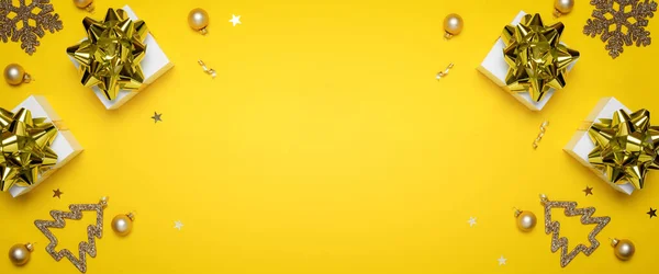Felice anno nuovo. Regali bianchi con fiocco dorato, palline gialle e luci scintillanti nella decorazione natalizia su sfondo giallo per biglietto di auguri. Natale, inverno, nuovo concetto di anno. — Foto Stock