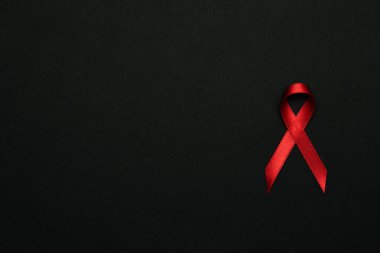 Farkındalık geçmişi. HIV Günü 'nde kırmızı kurdele sembolü koyu arkaplanda. Farkındalık yardımcıları ve kanser. Sağlık, tıbbi işaret. Boşluğu kopyala.