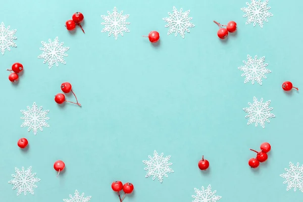 Weihnachtsmuster. Weiße Schneeflocken, rote Beeren in weihnachtlicher Komposition auf pastellblauem Hintergrund als Grußkarte. Winterfestliche Komposition mit Kopierraum. — Stockfoto