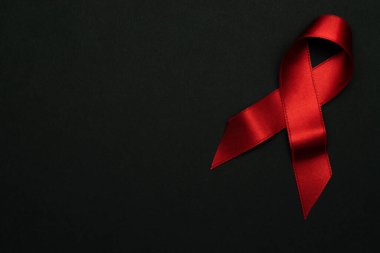 HIV virüsü. HIV Günü 'nde kırmızı kurdele sembolü koyu arkaplanda. Farkındalık yardımcıları ve kanser. Sağlık, tıbbi işaret. Boşluğu kopyala