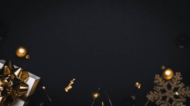 İyi tatiller. Altın yay, altın toplar ve parlak ışık çelenkleriyle dolu beyaz bir hediye. Karanlık arka planda tebrik kartı için. Uzayı kopyala Kış tatili, yeni yıl