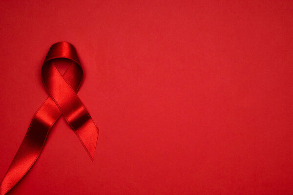 Awareness background. Red ribbon symbol in hiv world day on dark red background. Awareness aids and cancer. Health, Medical sign. copy space