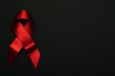 HIV desteği. HIV dünyasında siyah zemin üzerinde kırmızı kurdele sembolü. Farkındalık yardımcıları ve kanser. Yaşlanma Sağlık Ay konsepti