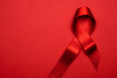 HIV desteği. HIV dünyasında kırmızı arkaplanda kırmızı kurdele sembolü. Farkındalık yardımcıları ve kanser. Yaşlanma Sağlık Ay konsepti