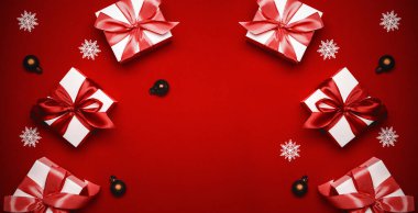 Hediye kurdele kutusu. Kırmızı kurdeleli beyaz hediye kutusu, yılbaşı baloları ve tebrik kartı için koyu kırmızı arka planda parlak ışıklar. Noel, kış, yeni yıl konsepti