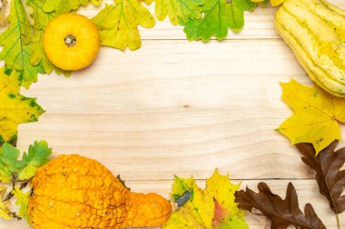 Şükran Günü tatili Turuncu balkabağıyla sonbahar hasadı, kurumuş yapraklar, kırmızı böğürtlen ve meşe palamudu, ahşap zeminde kestaneler. Mevsimlik teklifler ve tatil kartpostalı, üst görünüm