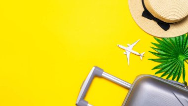 Deniz kabukları. Çanta, palmiye yaprakları ve hasır şapkalı güneş gözlüğü, sarı arka planda seyahat kompozisyonu olan beyaz bir uçak. Yol iskeleti hazır. Düz yatış, üst görünüm