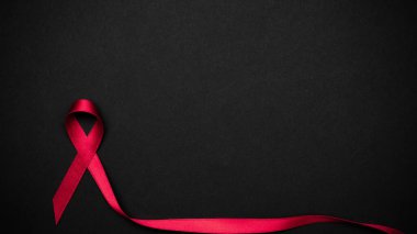 HIV desteği. HIV dünyasında siyah zemin üzerinde kırmızı kurdele sembolü. Farkındalık yardımcıları ve kanser. Yaşlanma Sağlık Ay konsepti