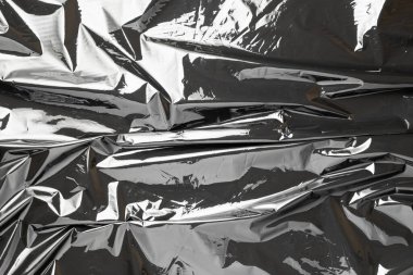 Plastik siyah arka plan. Şeffaf koyu selofanı sar. Siyah, parlak bir çanta deseni. Polietilen folyonun gerçek dokusu