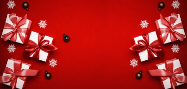 Hediye arka planı. Kırmızı kurdeleli beyaz hediye kutusu, yılbaşı baloları ve tebrik kartı için koyu kırmızı arka planda parlak ışıklar. Düz konum, üst görünüm, kopyalama alanı