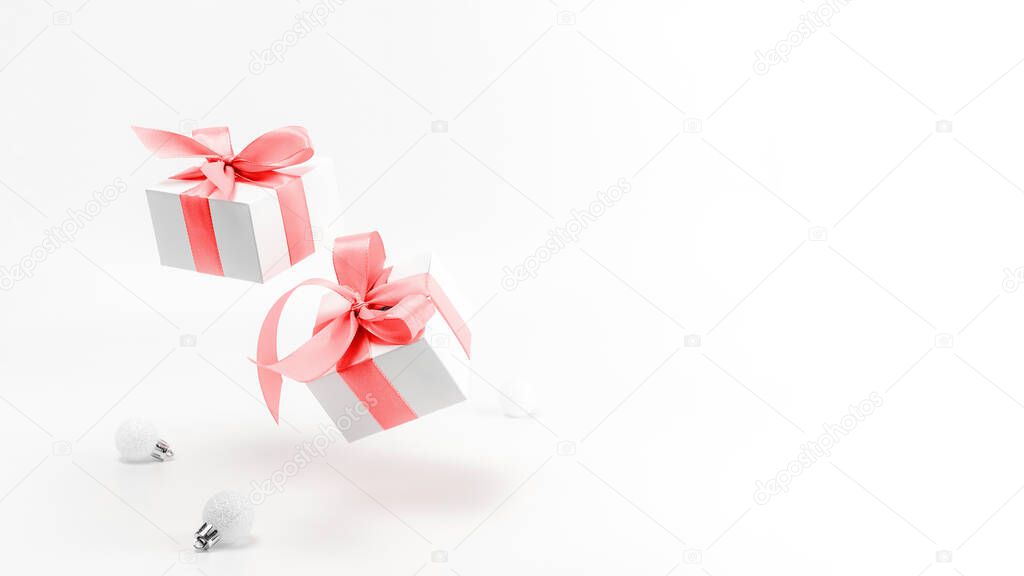 Holiday winter red. White gift box with red ribbon, New Year balls in Christmas composition on white background for greeting card. Copy space. Winter holidays, New Year
