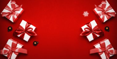 Hediye arka planı. Kırmızı kurdeleli beyaz hediye kutusu, yılbaşı baloları ve tebrik kartı için koyu kırmızı arka planda parlak ışıklar. Düz konum, üst görünüm, kopyalama alanı