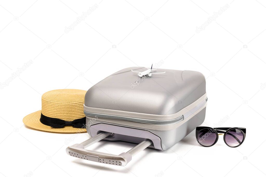 Summer time. Travel accessories with suitcase, straw hat, toy airplane in minimal trip vacation concept isolated on white background. Exotic tropical beach with copy space