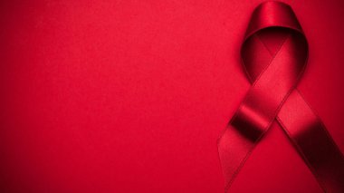 Kurdele ipeği. HIV dünyasında kırmızı arkaplanda kırmızı kurdele sembolü. Farkındalık yardımcıları ve kanser. Düz konum, üst görünüm, kopyalama alanı.